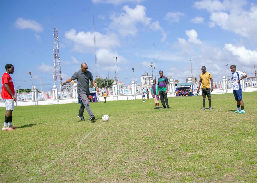 A guest taking the ceremonial kick-off on the College field