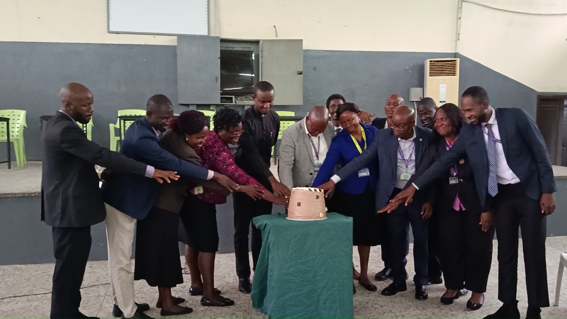 Staff reaching together to cut the Teachers' Day cake