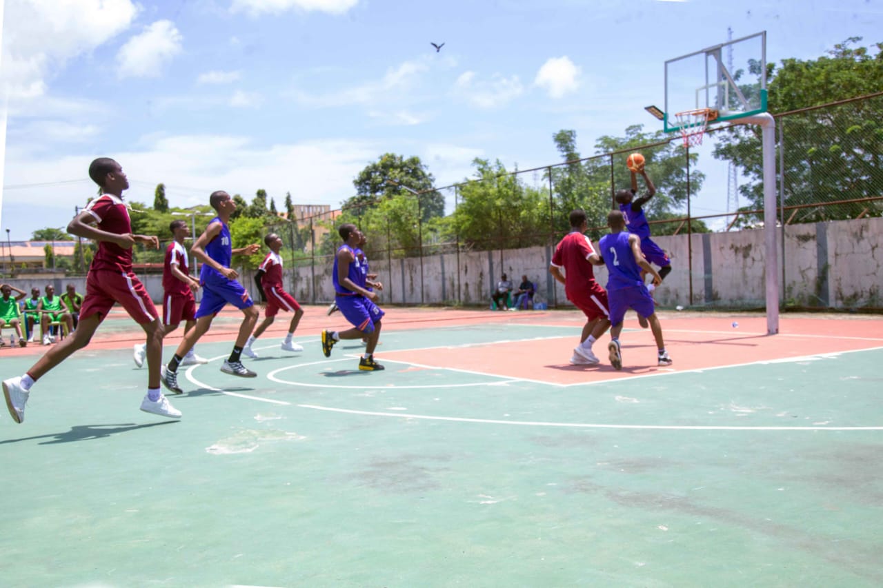 Basketball players in purple and maroon contesting a layup