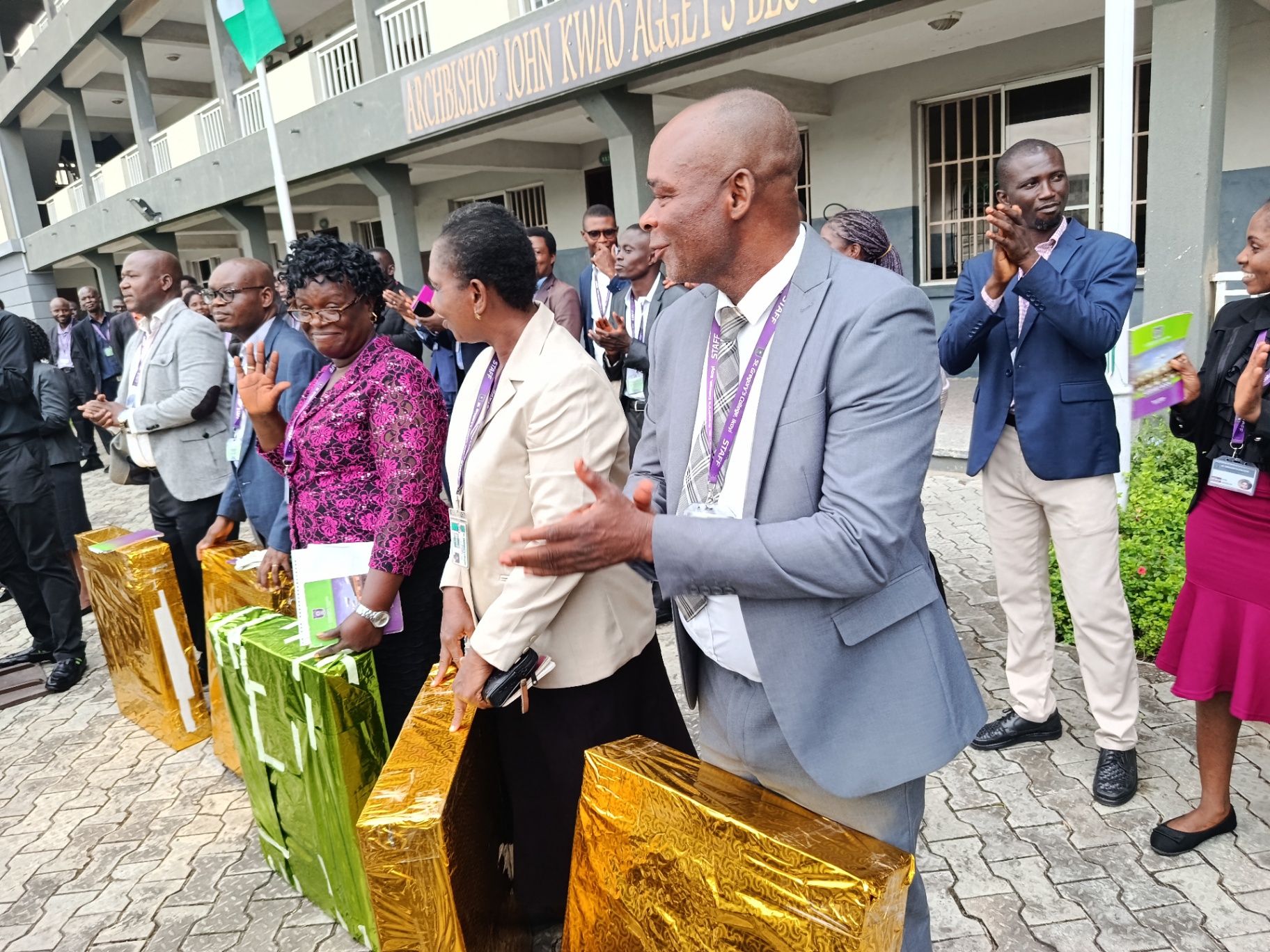 Staff members holding wrapped gifts while colleagues applaud