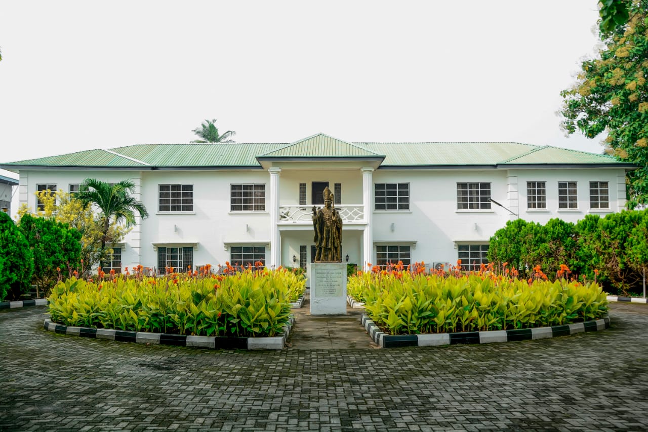 The white colonial-style administrative block with the bishop's statue in the forecourt
