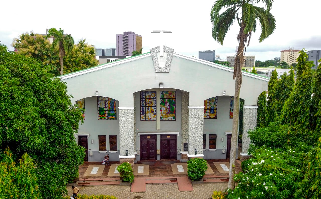 The College chapel with stained-glass windows and cross, framed by palms