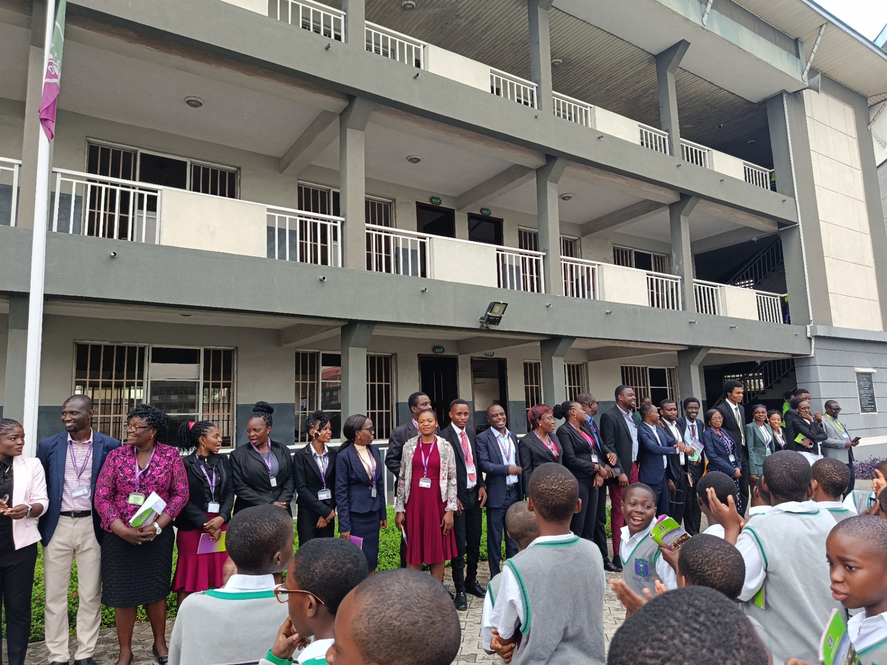 Teachers and staff lined up outside a College building as students gather