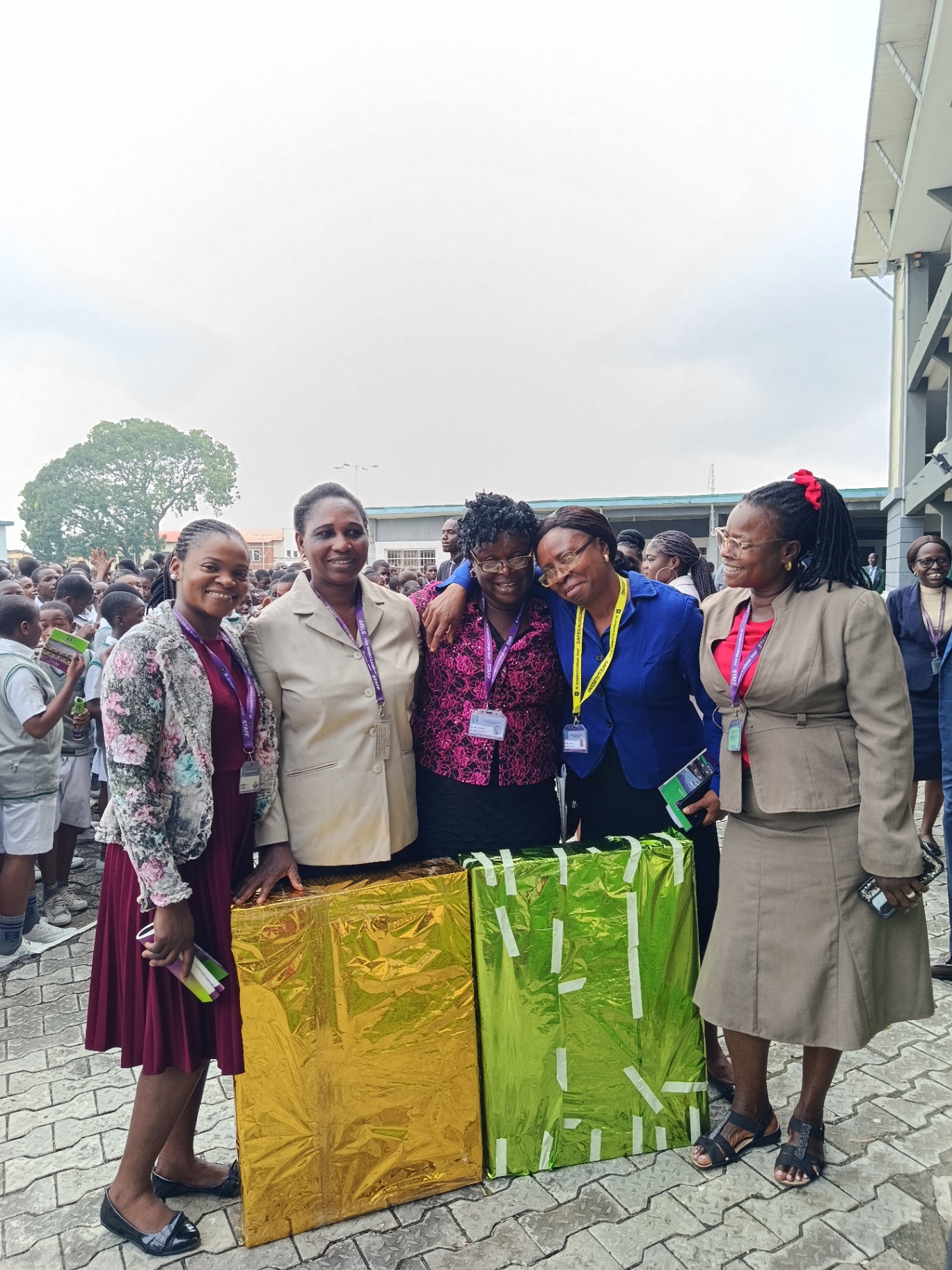 Five teachers smiling together beside wrapped gifts