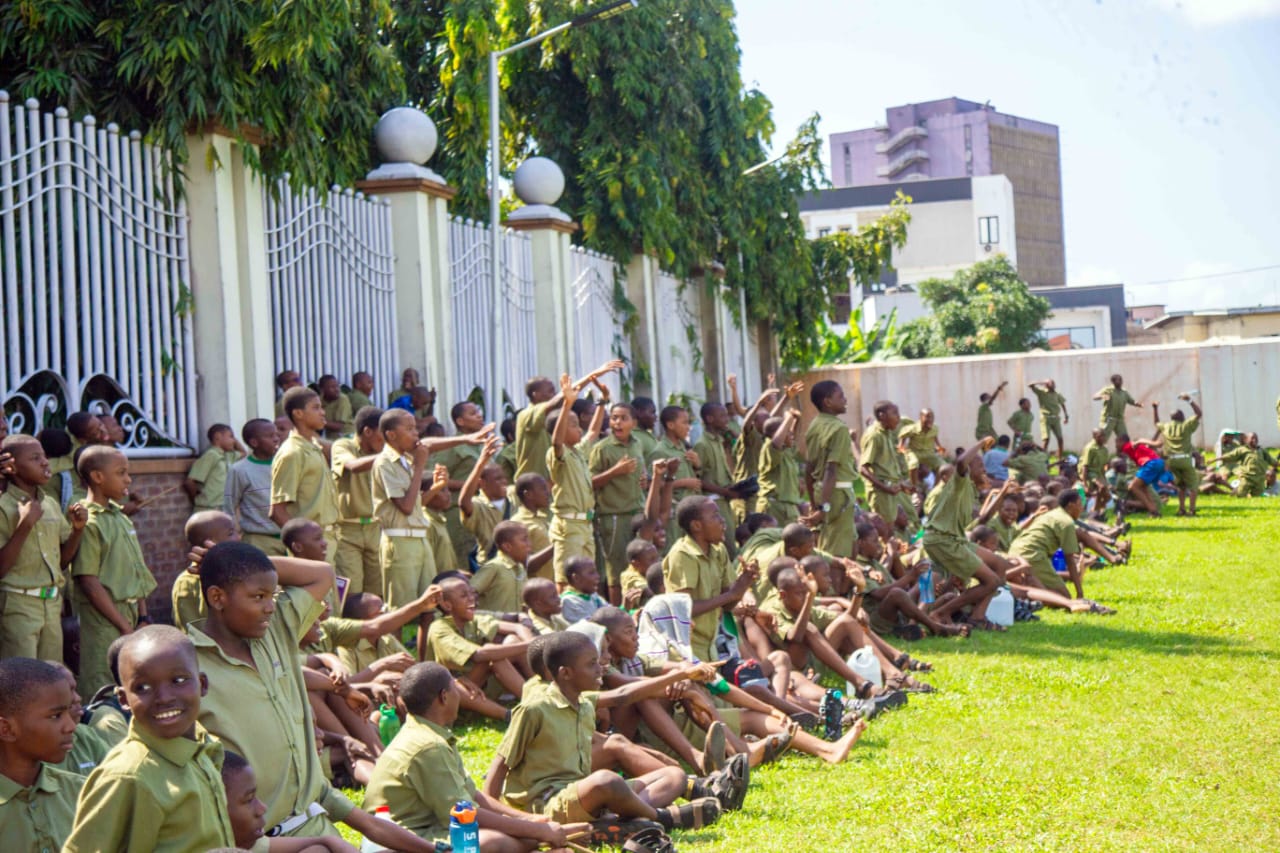 Students in uniform cheering from the grass beside the field