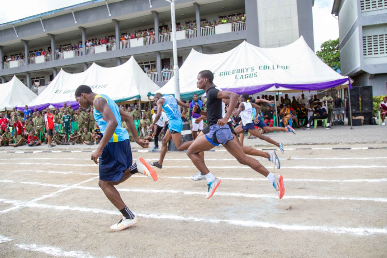 Athletes sprinting on the track in front of the St Gregory's College tents