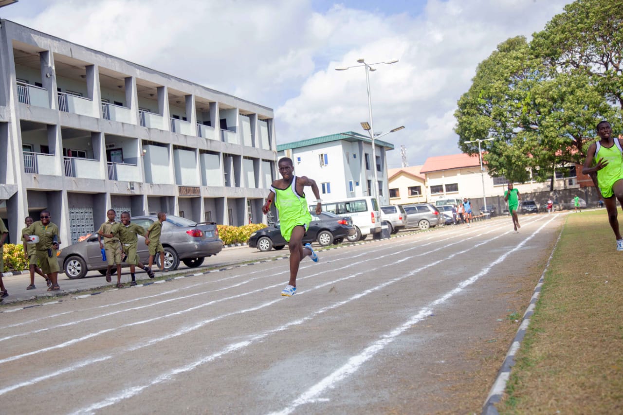 An athlete in a green vest running on the College track