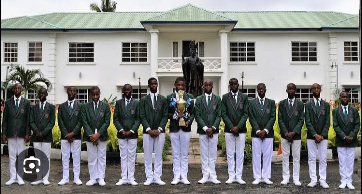 St. Gregory's College students in green blazers holding a trophy in front of the main building
