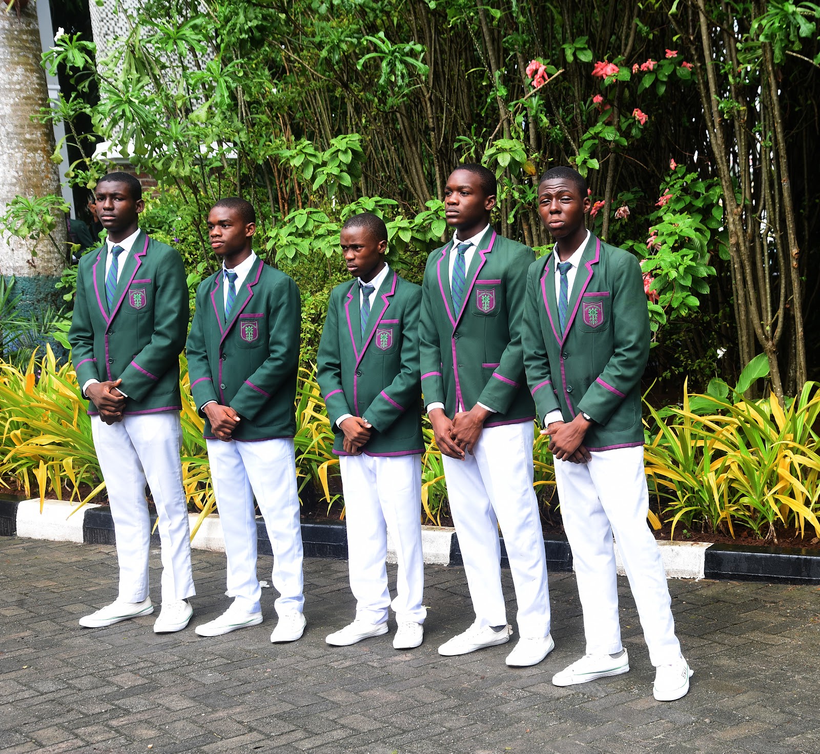 A line of students in green blazers standing in the College grounds
